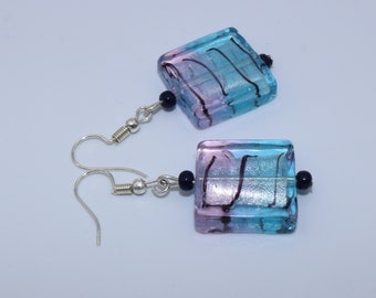 Handgemaakte oorbellen met vierkante tweekleurige glaskralen in roze tot lichtblauw verloop met zwarte lijnen