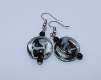 Handmade earrings with a flat round bead of transparent glass and a black heart with white accents