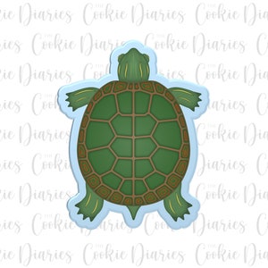 May include: A green and brown turtle cookie cutter with a detailed shell design. The cutter is made of metal and has a light blue background.