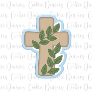 May include: A light blue cookie cutter in the shape of a cross with a brown cross and green leaves.