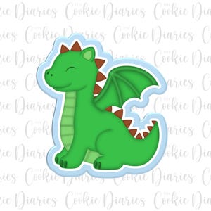 May include: A green dragon cookie cutter with brown accents and a light blue background. The dragon has a smiling face and wings.