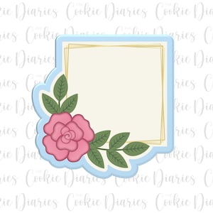 May include: A floral cookie cutter with a light blue scalloped border. The cutter features a pink rose and green leaves in the corner, with a gold rectangle inside. The text "Cookie Diaries" is in the background.