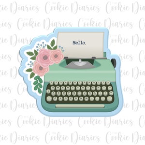 May include: A light blue vintage typewriter cookie cutter with a floral design. The typewriter has a light green body and black keys. The text "Hello." is printed on the top of the typewriter.