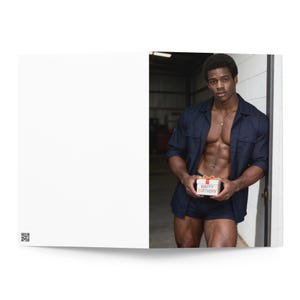May include: A greeting card featuring a dark-skinned individual wearing a navy blue button-down shirt and matching shorts, holding a small white gift box with a red ribbon and the text Happy Birthday printed on the front in colorful letters.