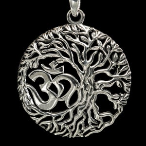 May include: A silver pendant featuring a tree of life design with an Om symbol in the centre. The pendant is round and has a detailed, intricate design.
