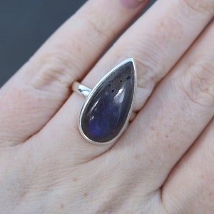 Può includere: Un anello d'argento a forma di lacrima con una pietra di labradorite blu scuro.