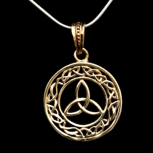 Könnte beinhalten: Goldene keltische Knoten-Halskette mit einem runden Design, das einen Trinitätsknoten zeigt. Der Anhänger ist an einer silbernen Kette.