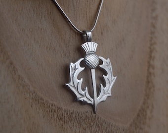 Puede incluir: Collar con colgante de plata con un diseño detallado de un cardo, la flor nacional de Escocia.