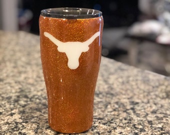 May include: A brown glitter tumbler with a white Texas Longhorns logo.