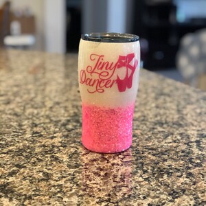 May include: A pink and white glitter tumbler with the text "Tiny Dancer" and a pink ballet shoe graphic.