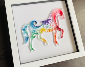 May include: A colorful paper quilling art piece depicting a horse with intricate floral designs. The horse is made of curled paper strips in shades of pink, blue, yellow, green, and purple.