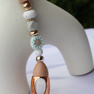 May include: A light blue and white beaded car charm with a wooden heart charm and a copper diffuser bottle.