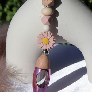 May include: Pink and wooden car air freshener with a pink flower charm and a wooden bead charm with a heart design.