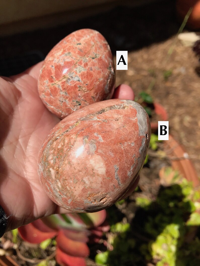 May include: Two red and white polished gemstone eggs, labeled A and B. The eggs are smooth and have a marbled pattern.