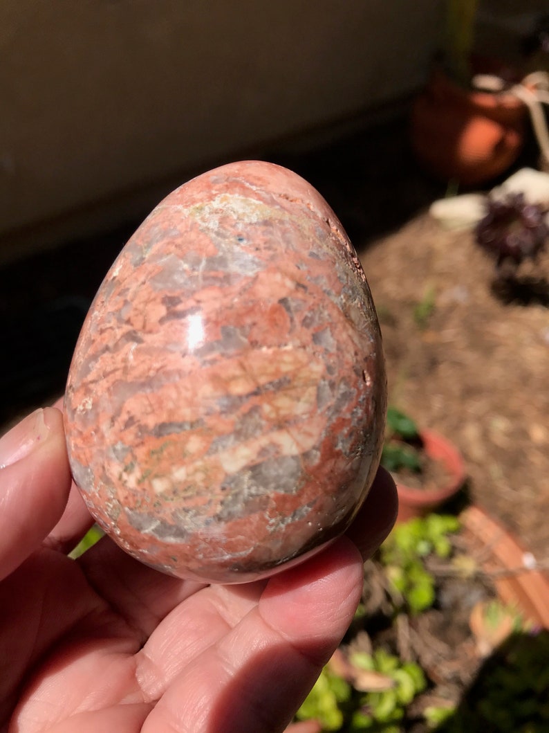 May include: A smooth, polished, pink and white egg-shaped stone with swirling patterns.