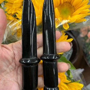 May include: Two black obsidian crystal daggers with rounded tips and polished handles.