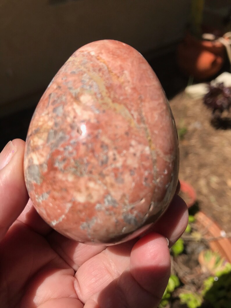 May include: A smooth, polished egg-shaped stone with a pink, white, and gray marbled pattern.