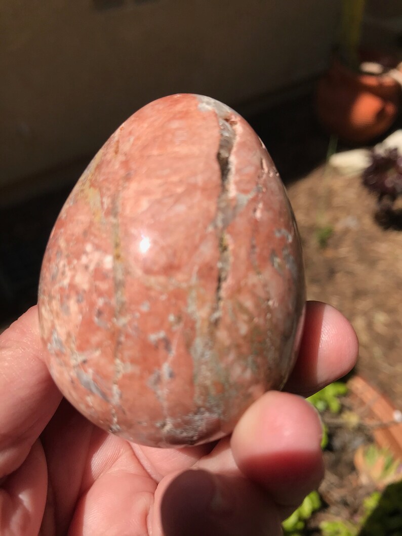 May include: A smooth, polished, pink and white egg-shaped stone with visible veins and striations.