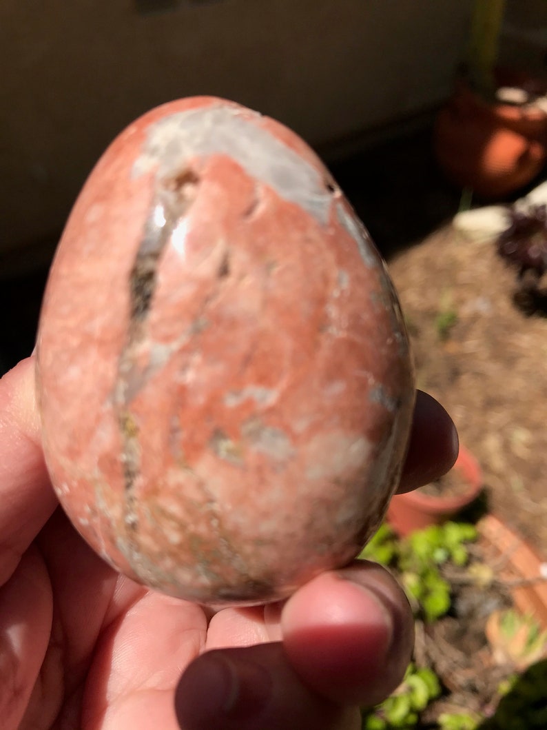May include: A smooth, polished, egg-shaped stone with a pink, white, and brown marbled pattern.
