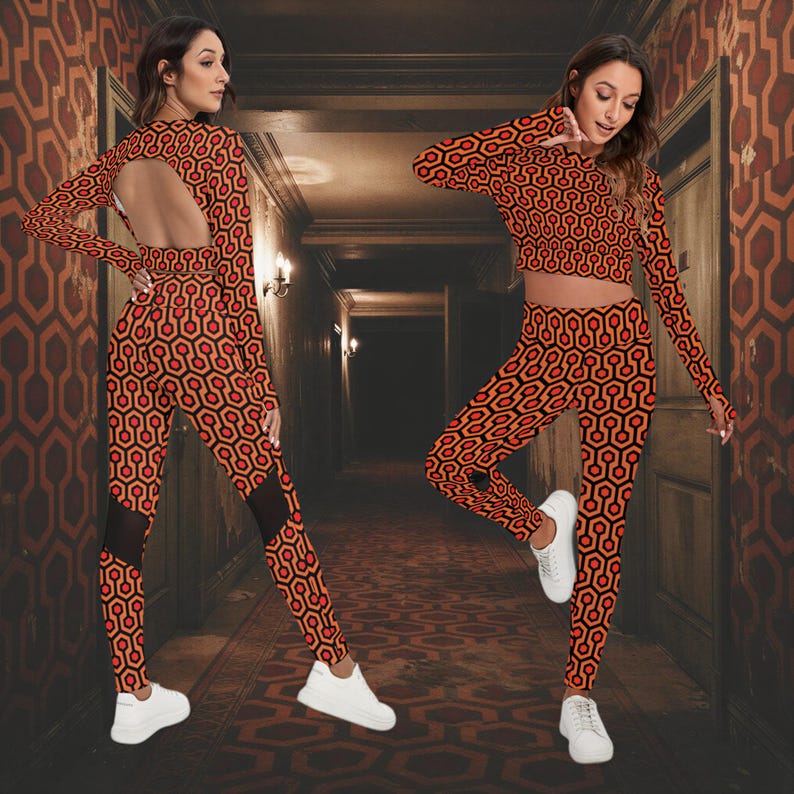A woman wearing a red and orange patterned outfit with a cutout back poses in a hallway.