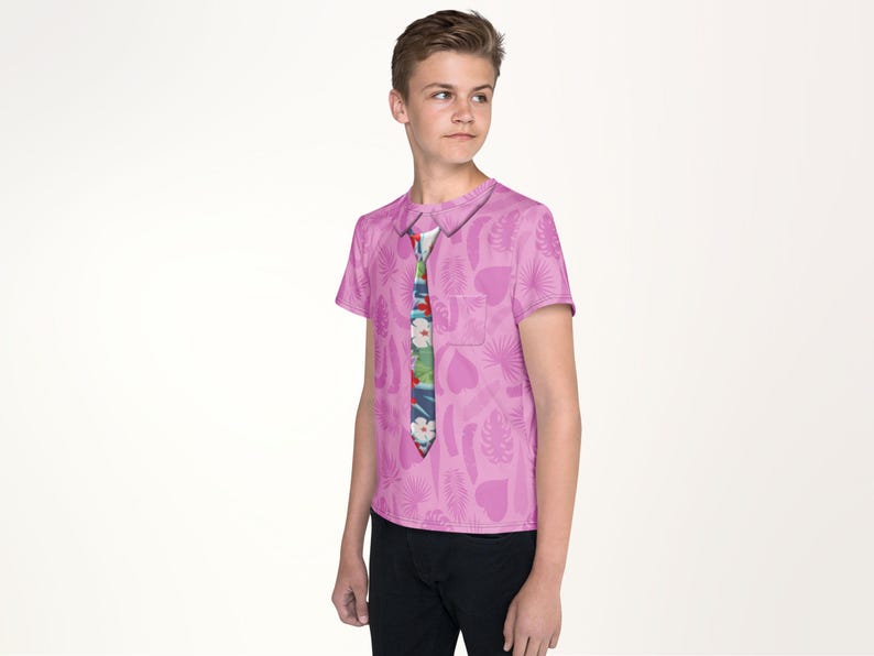 A young boy wearing a pink shirt with a tie pattern stands against a white background.