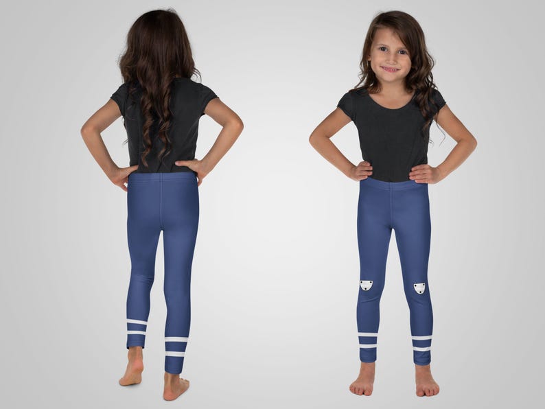 Puede incluir: Una ni&ntilde;a peque&ntilde;a lleva una camiseta negra de manga corta y leggings azules. Los leggings tienen rayas blancas en los tobillos y un gr&aacute;fico blanco en las rodillas. La ni&ntilde;a est&aacute; de pie con las manos en las caderas.