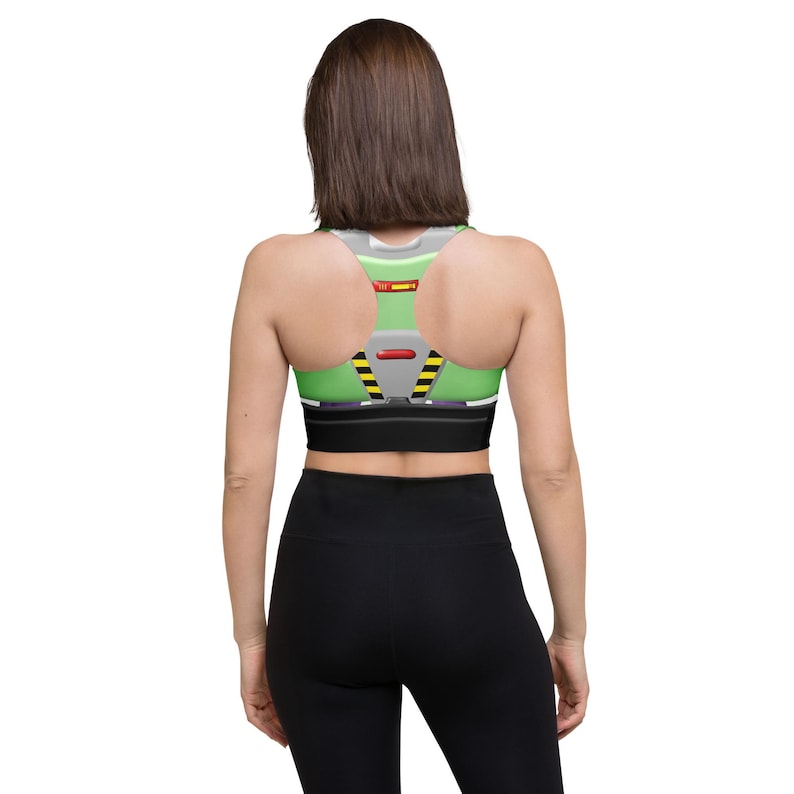 A woman wearing a green and black sports bra and black leggings, facing away from the camera.