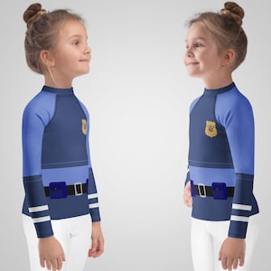 Puede incluir: Dos camisetas de manga larga para ni&ntilde;os con dise&ntilde;o de uniforme de polic&iacute;a. Las camisetas son principalmente azul marino con mangas azul claro y una secci&oacute;n media azul claro. Cada camiseta presenta una insignia dorada y un cintur&oacute;n negro con hebilla azul.