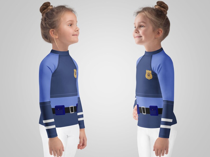 Puede incluir: Dos camisetas de manga larga para ni&ntilde;os con dise&ntilde;o de uniforme de polic&iacute;a. Las camisetas son principalmente azul marino con mangas azul claro y una secci&oacute;n media azul claro. Cada camiseta presenta una insignia dorada y un cintur&oacute;n negro con hebilla azul.