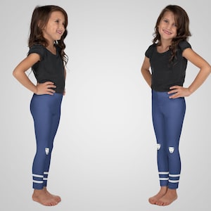 Puede incluir: Dos ni&ntilde;as peque&ntilde;as con conjuntos a juego. Cada ni&ntilde;a lleva una camiseta negra y leggings azules. Los leggings tienen un dibujo de oso blanco en las rodillas y rayas blancas en los tobillos. Las ni&ntilde;as est&aacute;n de pie frente a un fondo blanco.