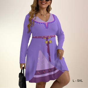 May include: A long-sleeved lavender dress featuring a V-neckline with a purple and pink geometric pattern. The waist is accented with a printed belt design including hanging tassels and gold-toned charms. The skirt has a darker purple hem.