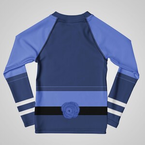 Puede incluir: Una camiseta de manga larga azul marino con mangas y detalles en azul claro. La camiseta presenta una franja horizontal azul claro, una franja negra y un dise&ntilde;o floral azul. Rayas blancas adornan las mangas.