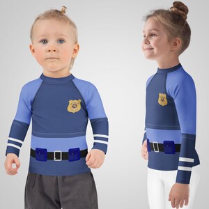 Puede incluir: Dos ni&ntilde;os con camisas de manga larga azul marino y azul claro con un dise&ntilde;o de insignia de polic&iacute;a. Las camisas tienen un dise&ntilde;o de cintur&oacute;n con dos bolsas azules y una hebilla plateada. Las mangas tienen rayas blancas.