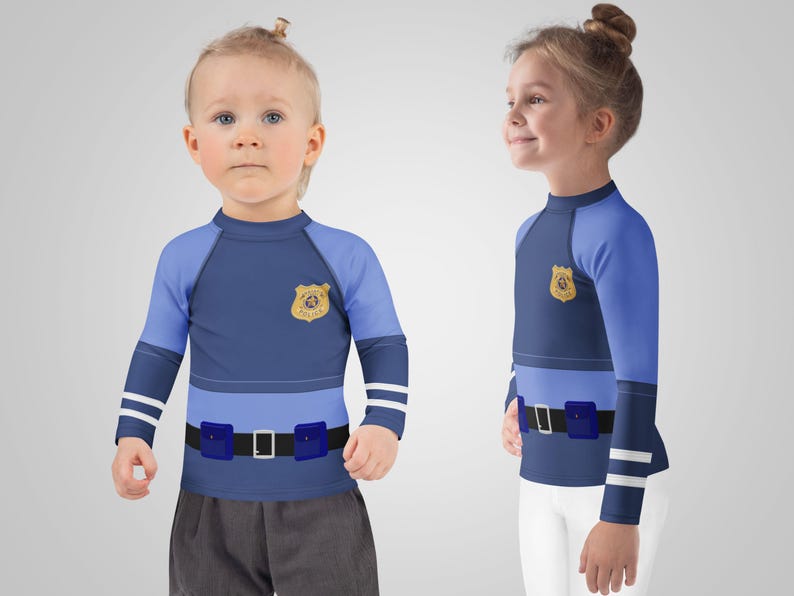 Puede incluir: Dos ni&ntilde;os con camisas de manga larga azul marino y azul claro con un dise&ntilde;o de insignia de polic&iacute;a. Las camisas tienen un dise&ntilde;o de cintur&oacute;n con dos bolsas azules y una hebilla plateada. Las mangas tienen rayas blancas.