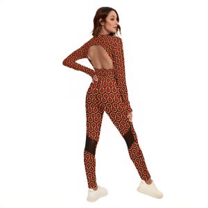 A woman wearing a long-sleeved jumpsuit with a cutout back, posing with her back to the camera.
