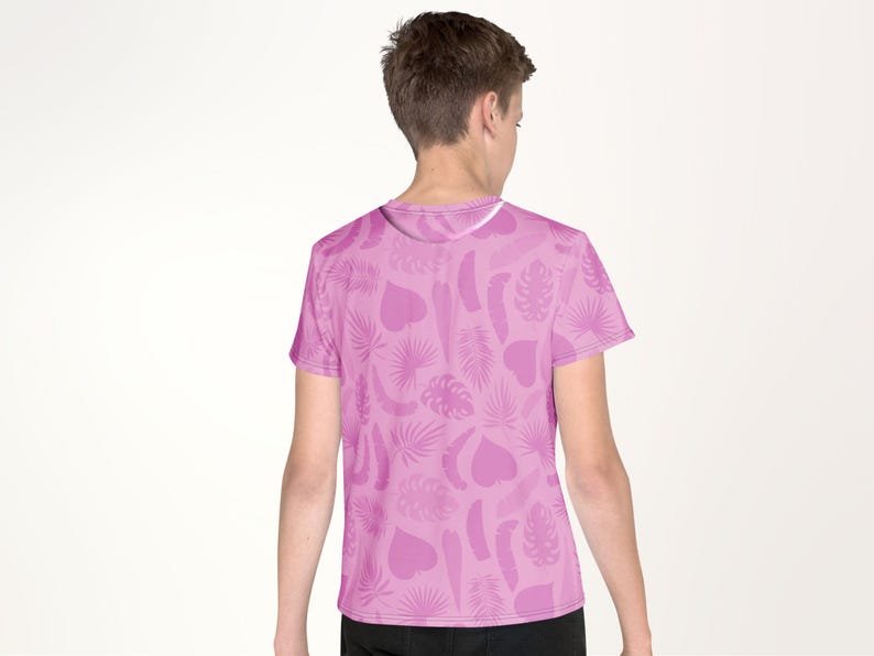 A person wearing a pink t-shirt with a pattern of leaves and hearts on it.