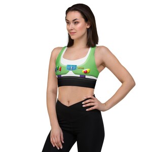 A woman wearing a green and white sports bra with colorful buttons and a red button on the front, posing confidently with her hands on her hips.