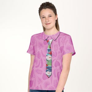 A young woman wearing a pink shirt with a tie printed on it, smiling at the camera.