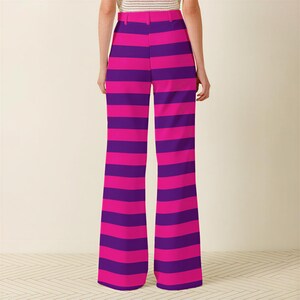 A person wearing a pair of wide-leg pants with a vibrant striped pattern in shades of pink and purple.