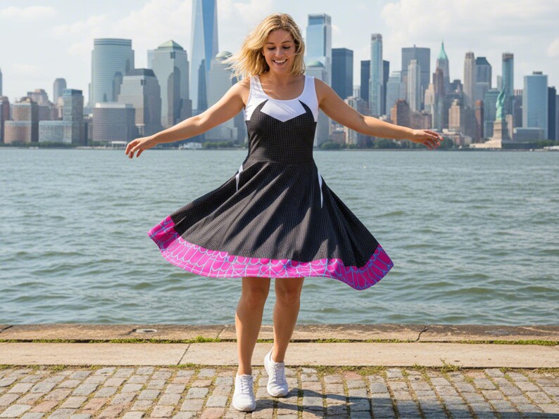 May include: A black and white dress with a pink and purple hem, featuring a spiderweb design. The dress has a white top with a geometric design. The background shows a cityscape and water.