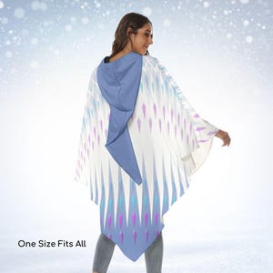 Pode incluir: Um poncho com capuz apresentando uma base branca com um padrão repetitivo de detalhes em forma de diamante nas cores azul, turquesa e roxo. A peça inclui um capuz azul sólido e traz o texto One Size Fits All.