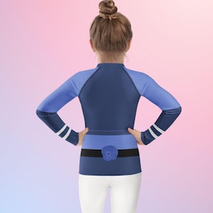 Puede incluir: Una camiseta de manga larga azul marino y azul claro con un detalle de rosa. La camiseta tiene rayas blancas en las mangas y un cintur&oacute;n negro con una rosa azul. El modelo lleva pantalones blancos.