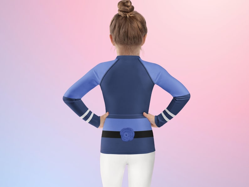 Puede incluir: Una camiseta de manga larga azul marino y azul claro con un detalle de rosa. La camiseta tiene rayas blancas en las mangas y un cintur&oacute;n negro con una rosa azul. El modelo lleva pantalones blancos.