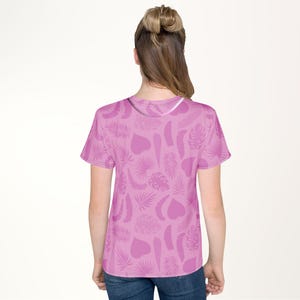 A woman wearing a pink t-shirt with a leaf pattern on it.