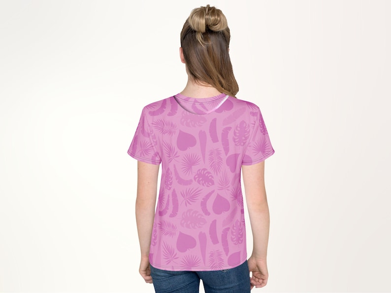 A woman wearing a pink t-shirt with a leaf pattern on it.