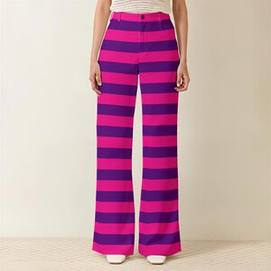 A person wearing a pair of wide-leg pants with a vibrant striped pattern in shades of pink and purple.