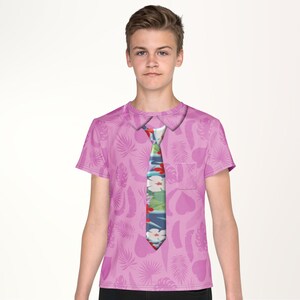 A young boy wearing a pink shirt with a tie printed on it.