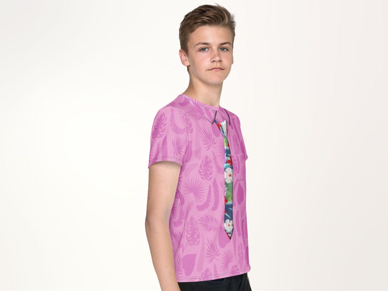 A young boy wearing a pink t-shirt with a colorful tie printed on it, posing for a portrait against a plain white background.