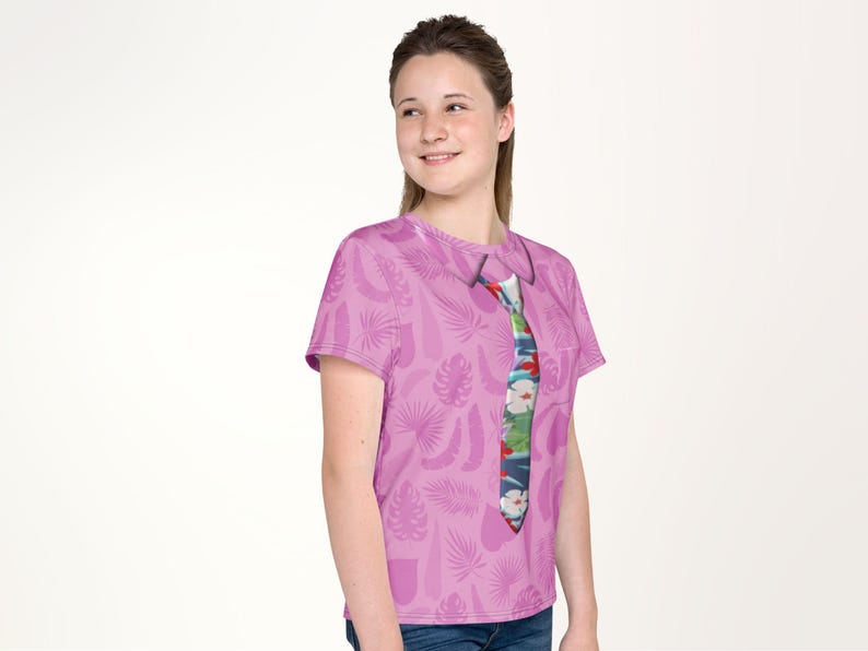 A young woman wearing a pink t-shirt with a colorful tie printed on it, smiling at the camera.
