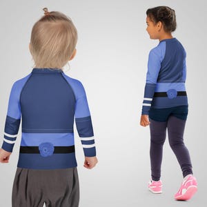 Puede incluir: Dos ni&ntilde;os con camisetas de manga larga y leggings. Las camisetas son principalmente azul marino con detalles en azul claro, un detalle de cintur&oacute;n negro y un adorno floral. Los leggings son de color gris oscuro. Un ni&ntilde;o lleva zapatillas rosas.
